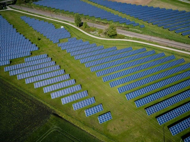 renewable energy aerial photography of grass field with blue solar panels